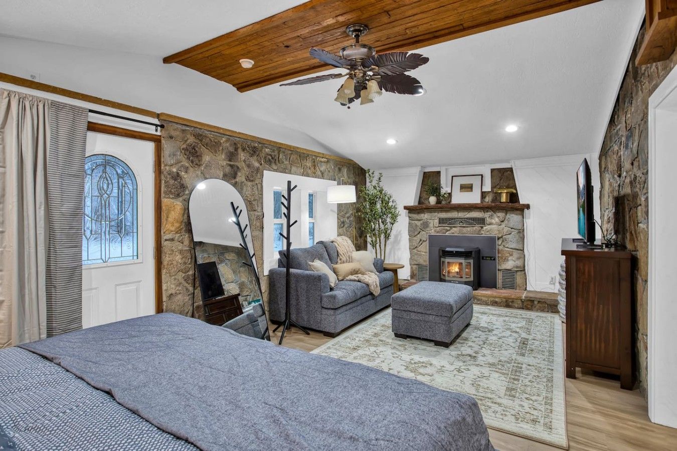A cozy living room with a fireplace, a sofa, a coffee table, and a ceiling fan.