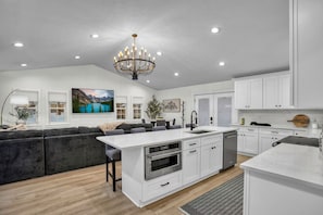 A modern kitchen with white cabinetry, a central island, and a chandelier.