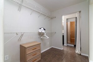 A room with a wooden dresser, a metal drying rack, and a door leading to a bathroom. - Shangri-La 6BR + Sleeps 16*Heated Pool/Spa (Tempe)