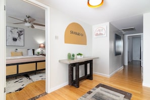 A modern interior with a sofa, a fireplace, a ceiling fan, and a hallway leading to another room. - Shangri-La 6BR + Sleeps 16*Heated Pool/Spa (Tempe)