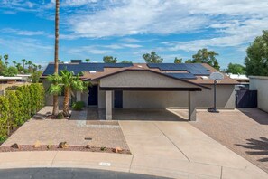 Una propiedad residencial con un porche cubierto, paneles solares y una canasta de baloncesto.