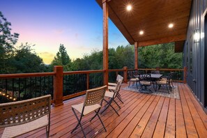Una terraza de madera con una mesa y sillas, rodeada por una barandilla.