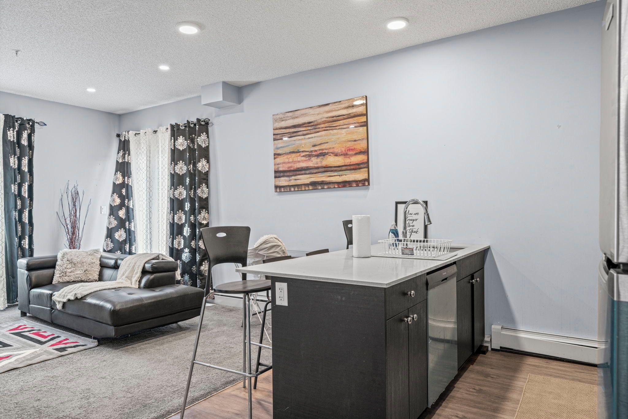 A modern living room with a sofa, a dining area with a table, and a kitchen with a sink.