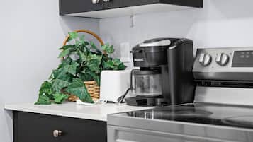 A kitchen with a coffee maker, a potted plant, and a white countertop.