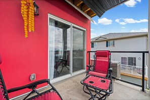 Un bâtiment rouge avec une porte coulissante en verre, une chaise rouge et un auvent rouge.