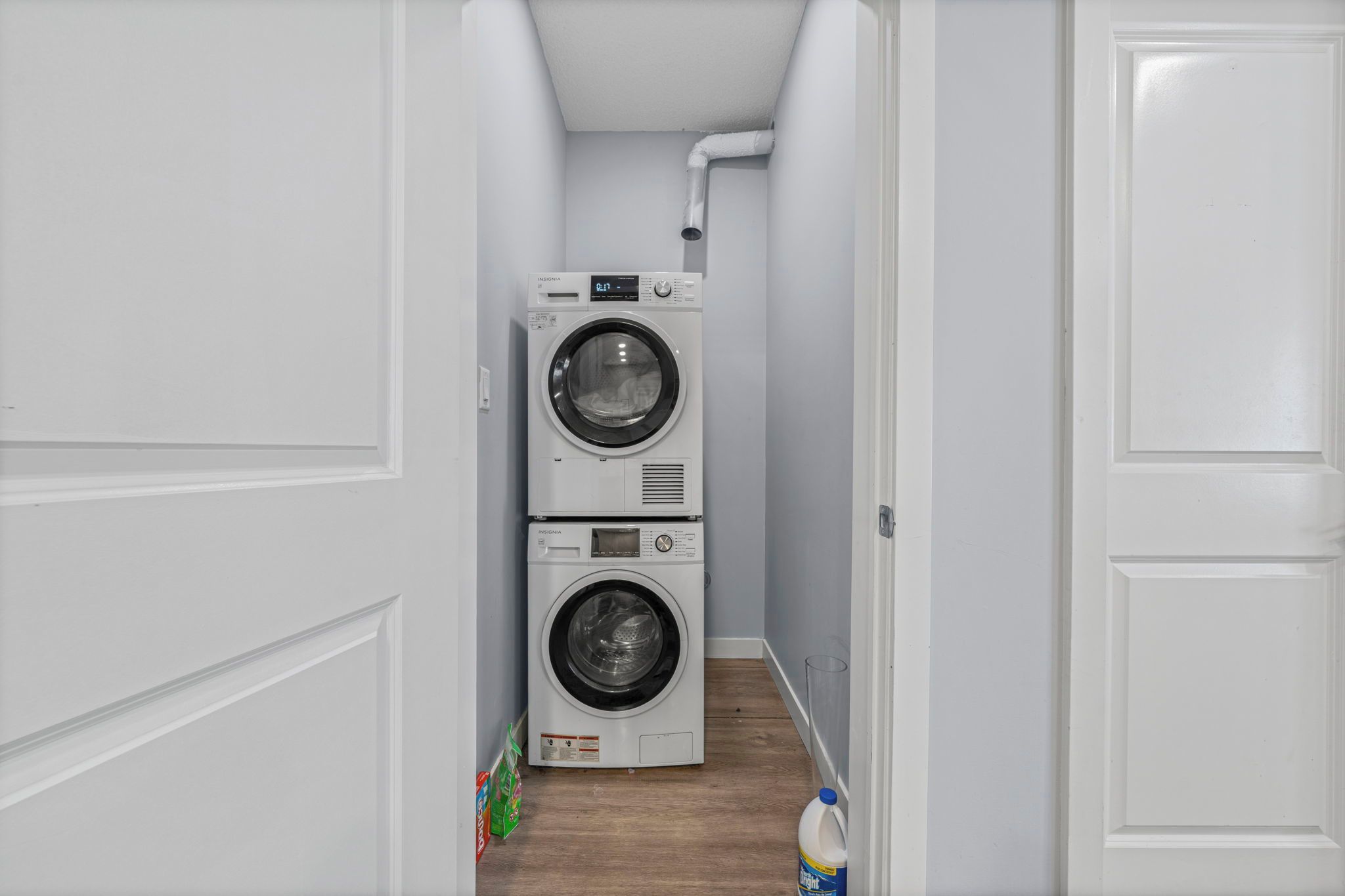 A laundry room with two stacked washing machines and a water bottle on the floor.
