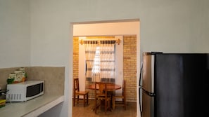 A compact kitchen with a microwave, refrigerator, and a dining area with chairs and a table.
