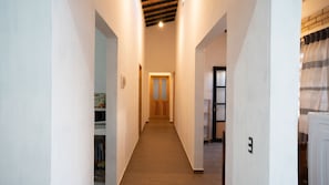 Un pasillo estrecho con una puerta de madera al final, que conduce a una habitación con suelo de baldosas.