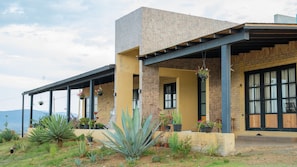 Una casa moderna con porche cubierto, fachada de piedra y vistas a las montañas.