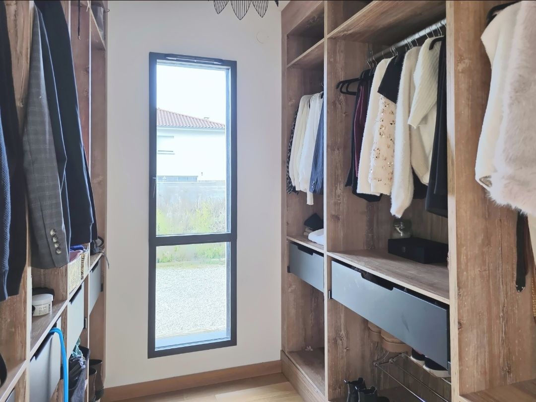Een inloopkast met houten planken en een groot raam.
