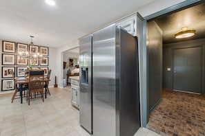 A kitchen with a stainless steel refrigerator, a dining table with chairs, and a chandelier. - Charming 3-bedroom house in adorable Edmond with quick access to I-35 or US-77 (Edmond)