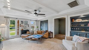 Un salon spacieux doté d’un ventilateur de plafond, d’une cheminée, d’une grande fenêtre et offrant une vue sur l’extérieur.