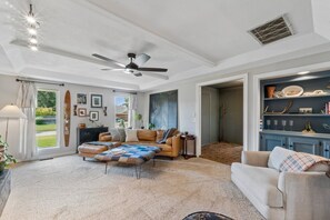 Un salón amplio con ventilador de techo, chimenea, ventana grande y vistas al exterior.