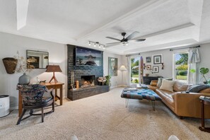 A living room with a fireplace, a ceiling fan, and a large window. - Charming 3-bedroom house in adorable Edmond with quick access to I-35 or US-77 (Edmond)