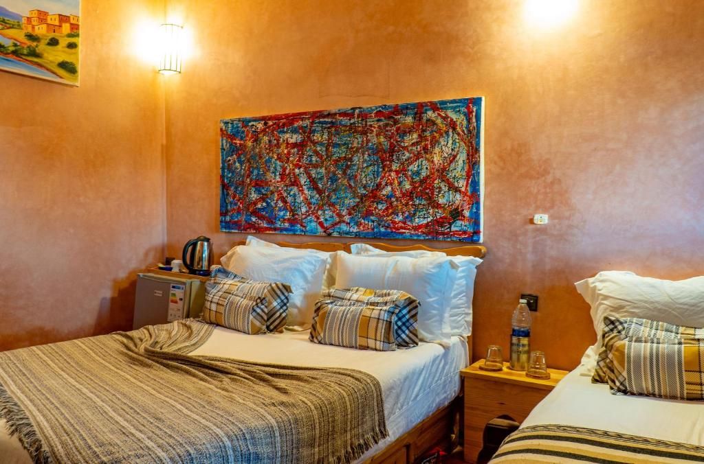 A hotel room with a bed, a bedside table, a lamp, a painting on the wall, and a window.