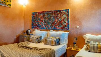 A hotel room with a bed, a bedside table, a lamp, a painting on the wall, and a window.
