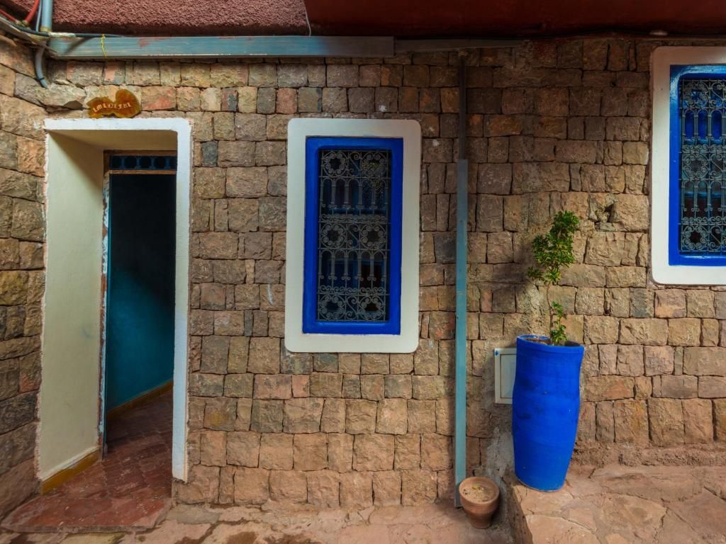 A stone building with a door and two windows with blue frames.