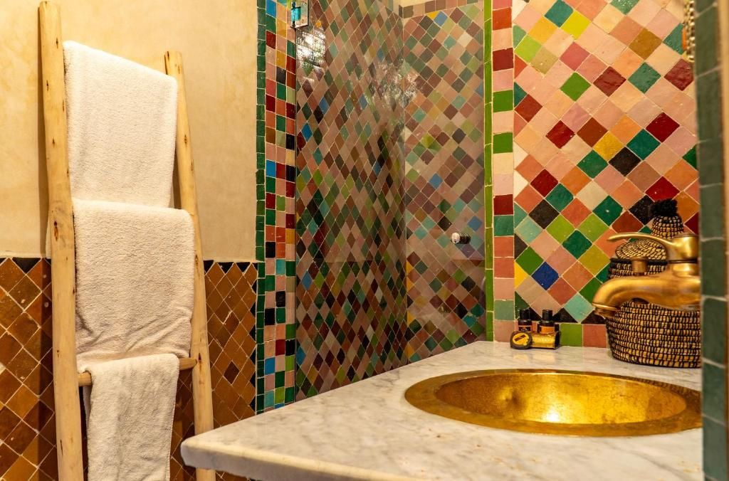 Ein Badezimmer mit Marmorwaschbecken, einem Handtuchhalter und farbenfrohen Mosaikfliesen.