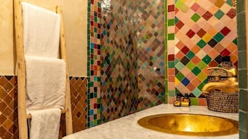 A bathroom with a marble sink, a towel rack, and colorful mosaic tiles.
