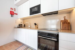 A modern kitchen with white cabinets, a built-in oven, a microwave, and a coffee maker. - Les Terrasses B / Private Rooftop Pool in Tavira (Faro)