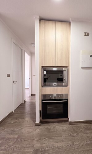 A kitchen with built-in appliances, including a microwave and oven, and a wooden cabinet above. - Edificio Link Ecuador by Domus Travels (Estación Central)