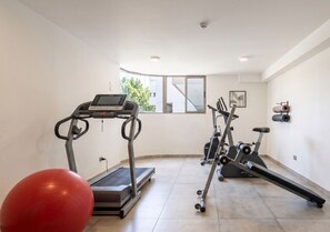 Een sportruimte met een loopband, elliptische trainer en een hometrainer.