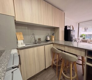 A modern kitchen with wooden cabinets, a stainless steel sink, and a black refrigerator. - Edificio Link Ecuador by Domus Travels (Estación Central)
