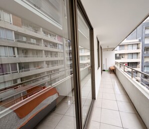 A corridor with a view of a multi-story building, a bench, and a broom on the floor. - Edificio Link Ecuador by Domus Travels (Estación Central)