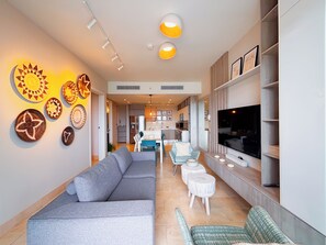 A modern living room with a grey sofa, a TV, and decorative wall art. - Coastal Paradise 2BR Marina View (Rio Hato)