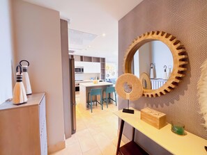 A modern kitchen with white cabinets, a microwave, and a dining area with blue chairs. - Coastal Paradise 2BR Marina View (Rio Hato)