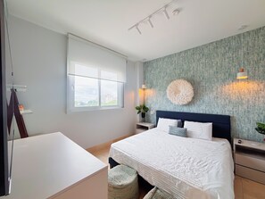 A bedroom with a bed, bedside tables, a window, and a view of buildings outside. - Coastal Paradise 2BR Marina View (Rio Hato)