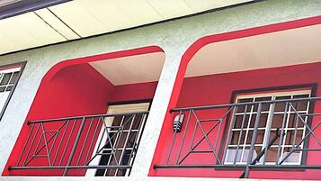A building with a red facade, multiple windows with metal bars, and a visible door.