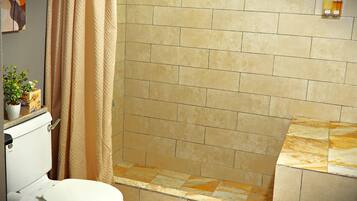 Une salle de bain équipée de toilettes, d’une douche et d’un porte-serviettes.