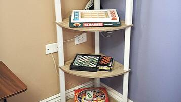 A corner shelf with a Scrabble box, a chess set, and a small cactus.