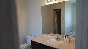 A bathroom with a toilet, a sink, and a mirror. - Charming GTA Retreat| Near Airport and Wonderland (Brampton)