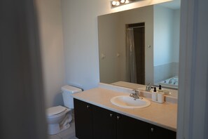 Un baño con inodoro, lavamanos y espejo.
