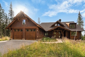 Eine große Holzhütte mit Garage, überdachter Veranda und geneigtem Dach.