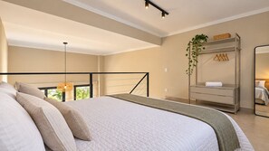 A bedroom with a large bed, a hanging light fixture, a wardrobe, and a mirror. - LOFT 10 (Vinhedo)