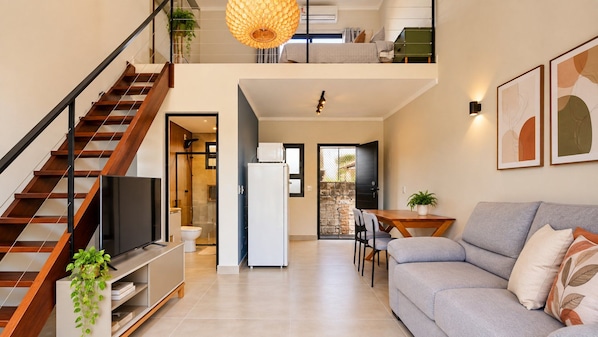 A modern living space with a staircase, a flat-screen TV, a dining area, and a sofa. - LOFT 10 (Vinhedo)