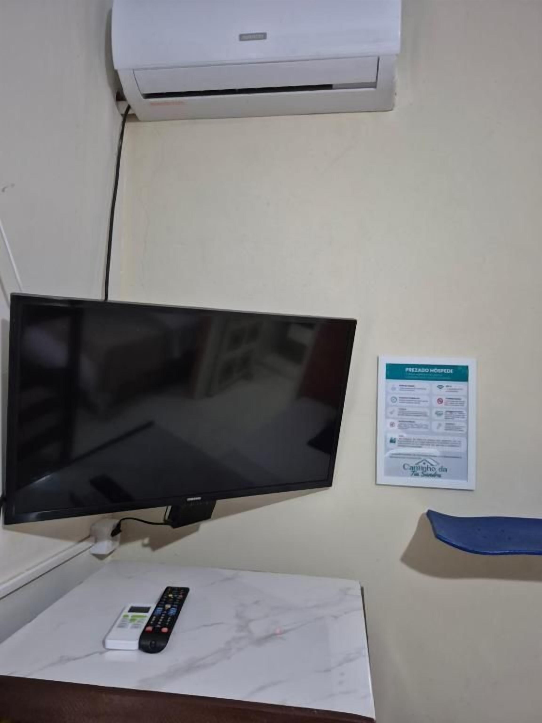 Ein an der Wand befestigter Fernseher, eine Fernbedienung auf einer Marmorplatte und ein Schild mit Text.