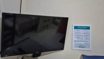 Un televisor montado en la pared, un control remoto sobre una superficie de mármol y un letrero con texto.