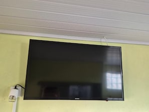 A flat-screen TV mounted on a wall with a power cord plugged in. - Pousada Cantinho da Tia Sandra (São Francisco do Sul)
