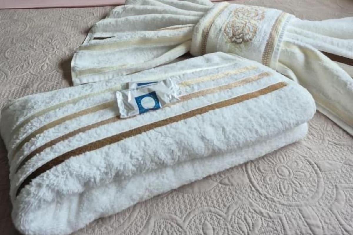 Een bed met een roze kussen en een witte deken met bruine strepen.