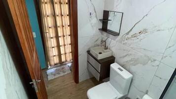 Casa de banho com sanita, lavatório e espelho.