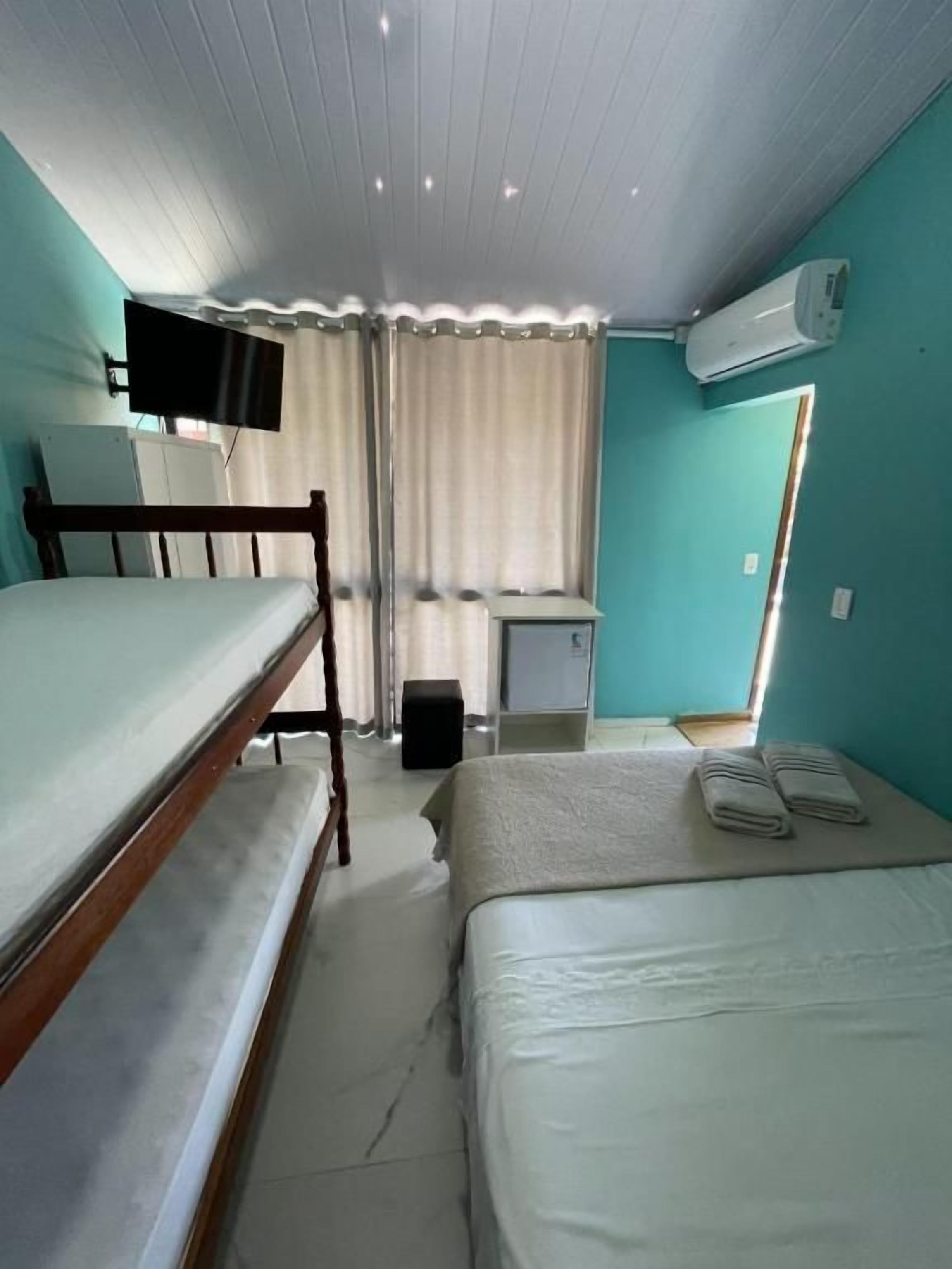 Ein Zimmer mit zwei Betten, einem Schreibtisch, einem Fernseher und einer Klimaanlage.