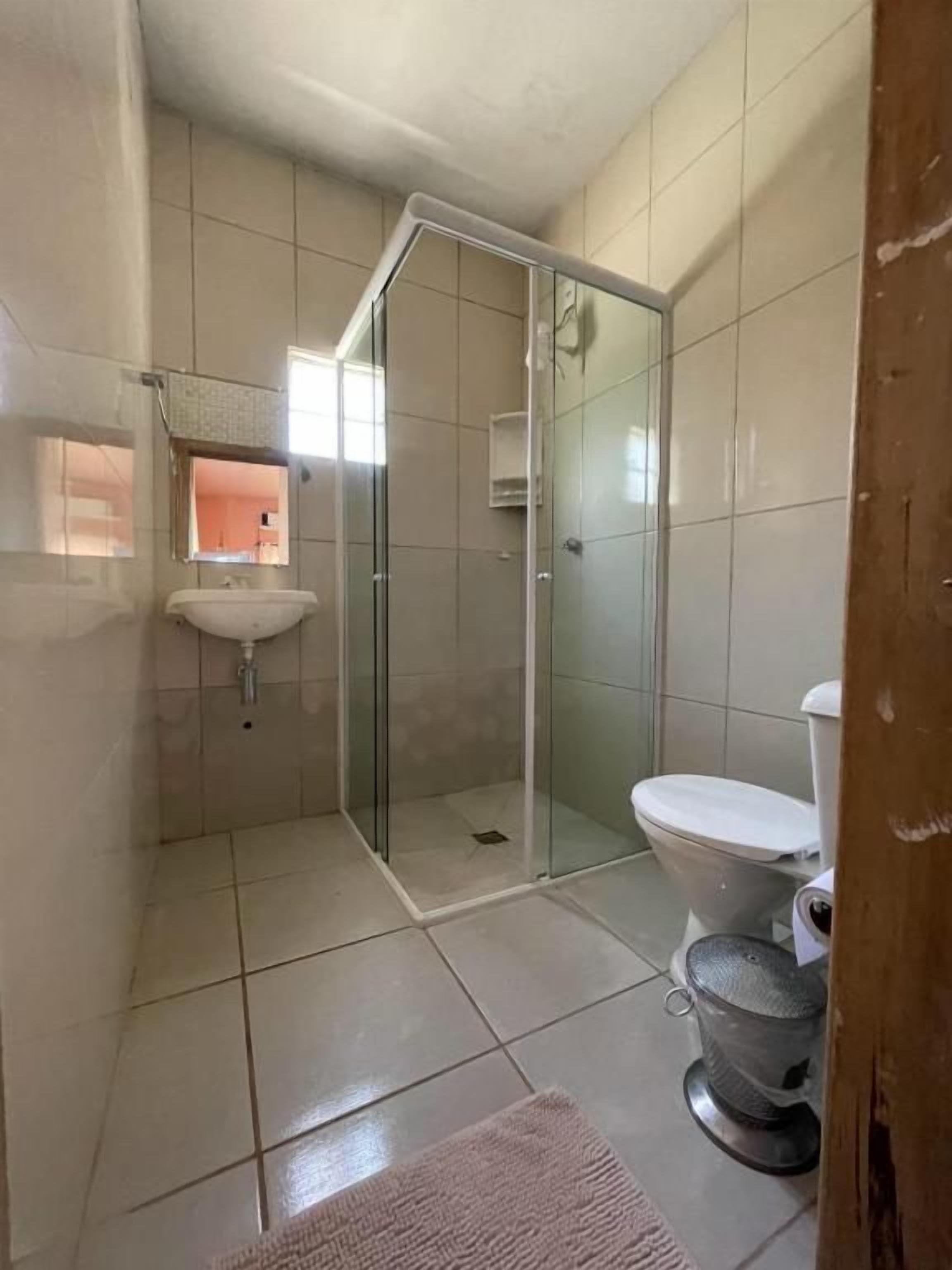 Casa de banho com cabine de chuveiro em vidro, sanita e lavatório.