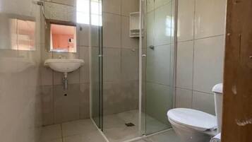 Casa de banho com cabine de chuveiro em vidro, sanita e lavatório.