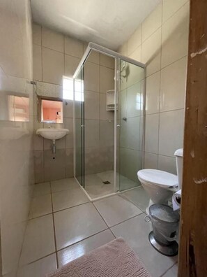 A bathroom with a glass shower enclosure, a toilet, and a sink.