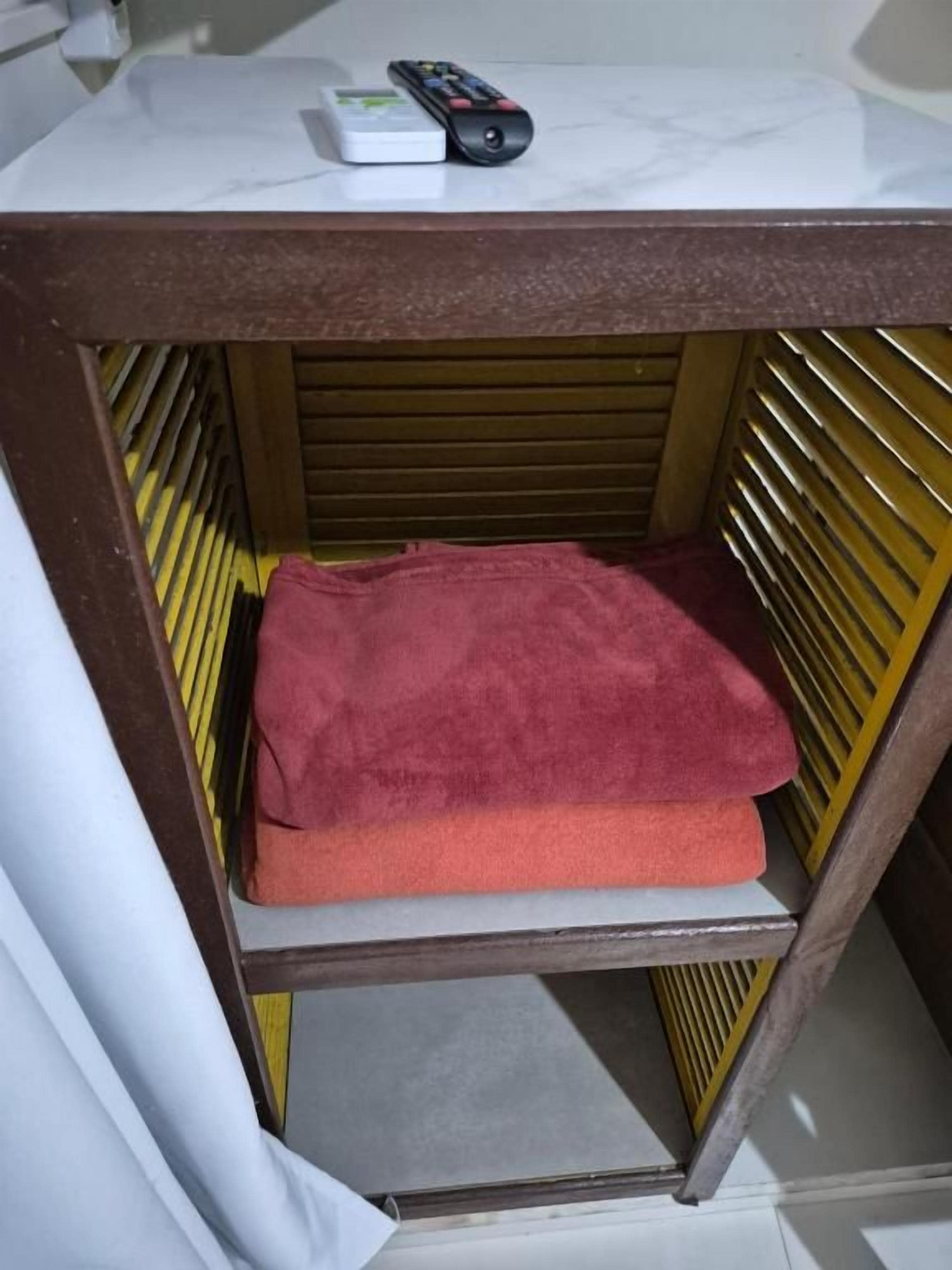 Una estantería con una toalla roja y un control remoto.