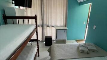 A room with two beds, a desk, a TV, and an air conditioning unit.